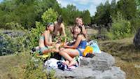 Teen-Age-girls find a friendly rock on which to perch while picnicking and swimming at The Coffey Grounds
