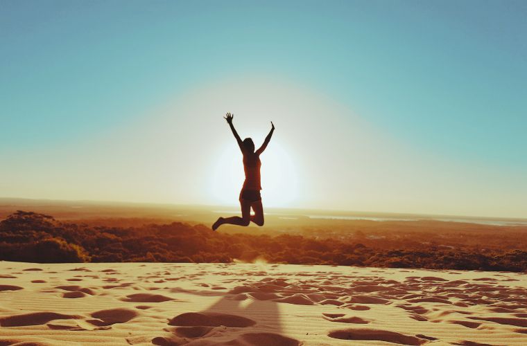 person jumping in front of sun